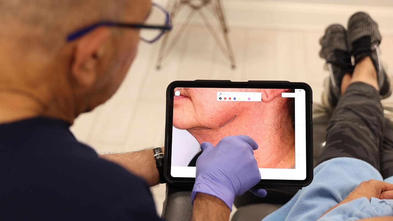 Dr. Nasra mapping the jawline and neck on a tablet during a XERF consultation